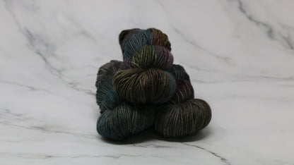 Three skeins of multicolored yarn on a white marble surface