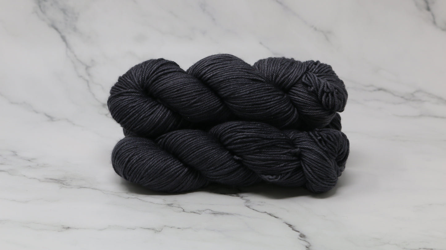 3 skeins of dark grey yarn on a marble surface and background