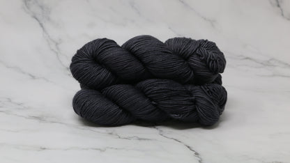 3 skeins of dark grey yarn on a marble surface and background