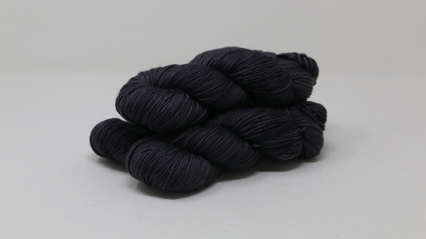 3 skeins of dark grey yarn on a white surface and background