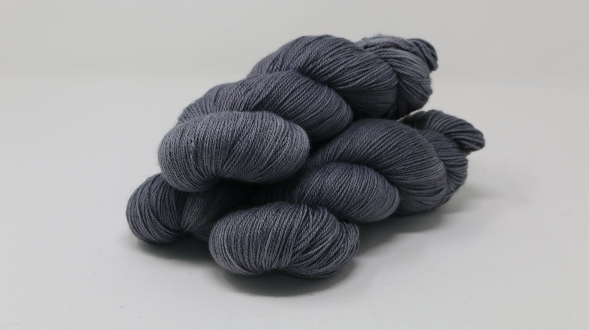Three skeins of yarn in a tonal dark grey colour