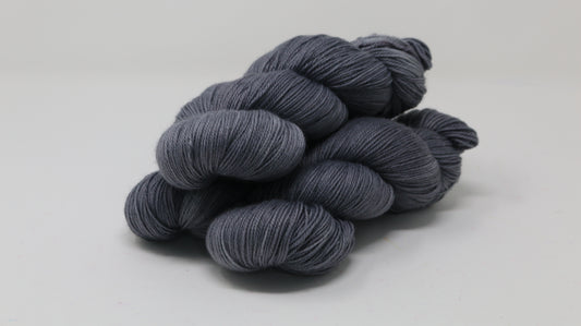 Three skeins of yarn in a tonal dark grey colour
