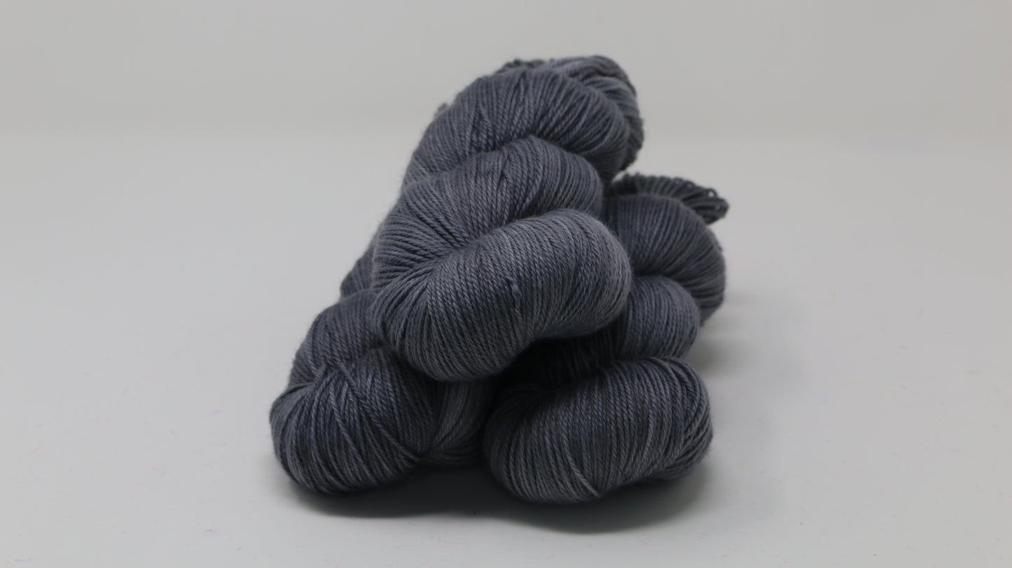 Three skeins of yarn in a tonal dark grey colour