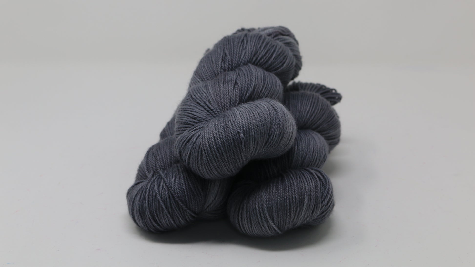 Three skeins of yarn in a tonal dark grey colour