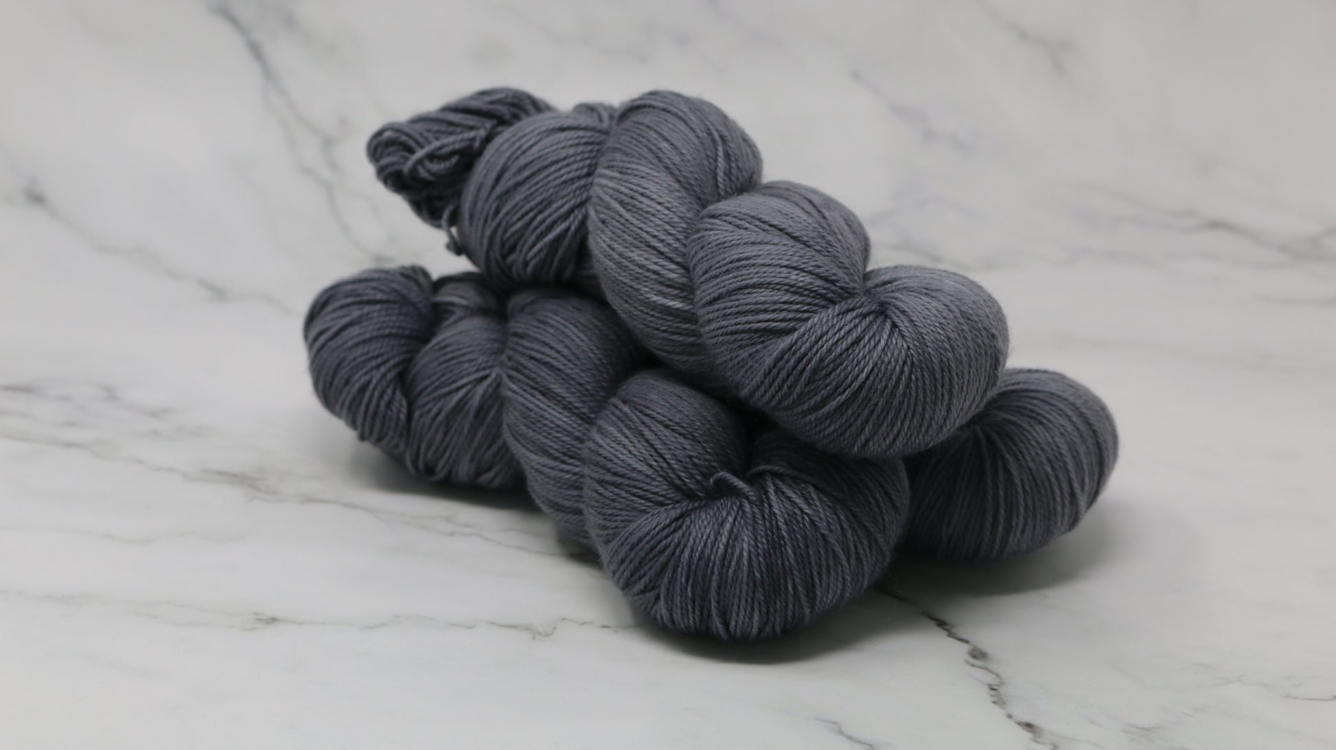 Three skeins of yarn in a tonal dark grey colour