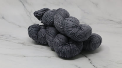 Three skeins of yarn in a tonal dark grey colour