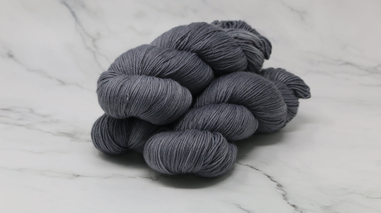Three skeins of yarn in a tonal dark grey colour