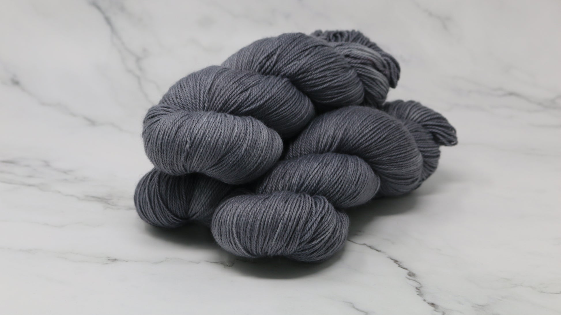 Three skeins of yarn in a tonal dark grey colour