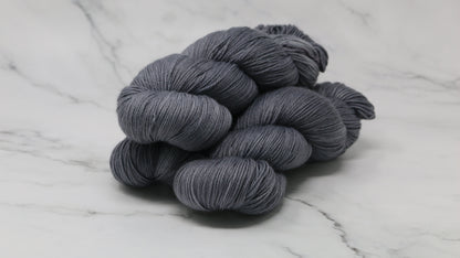 Three skeins of yarn in a tonal dark grey colour