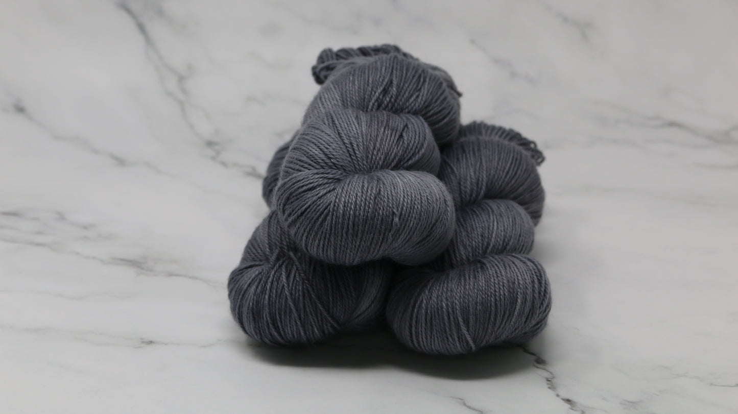 Three skeins of yarn in a tonal dark grey colour