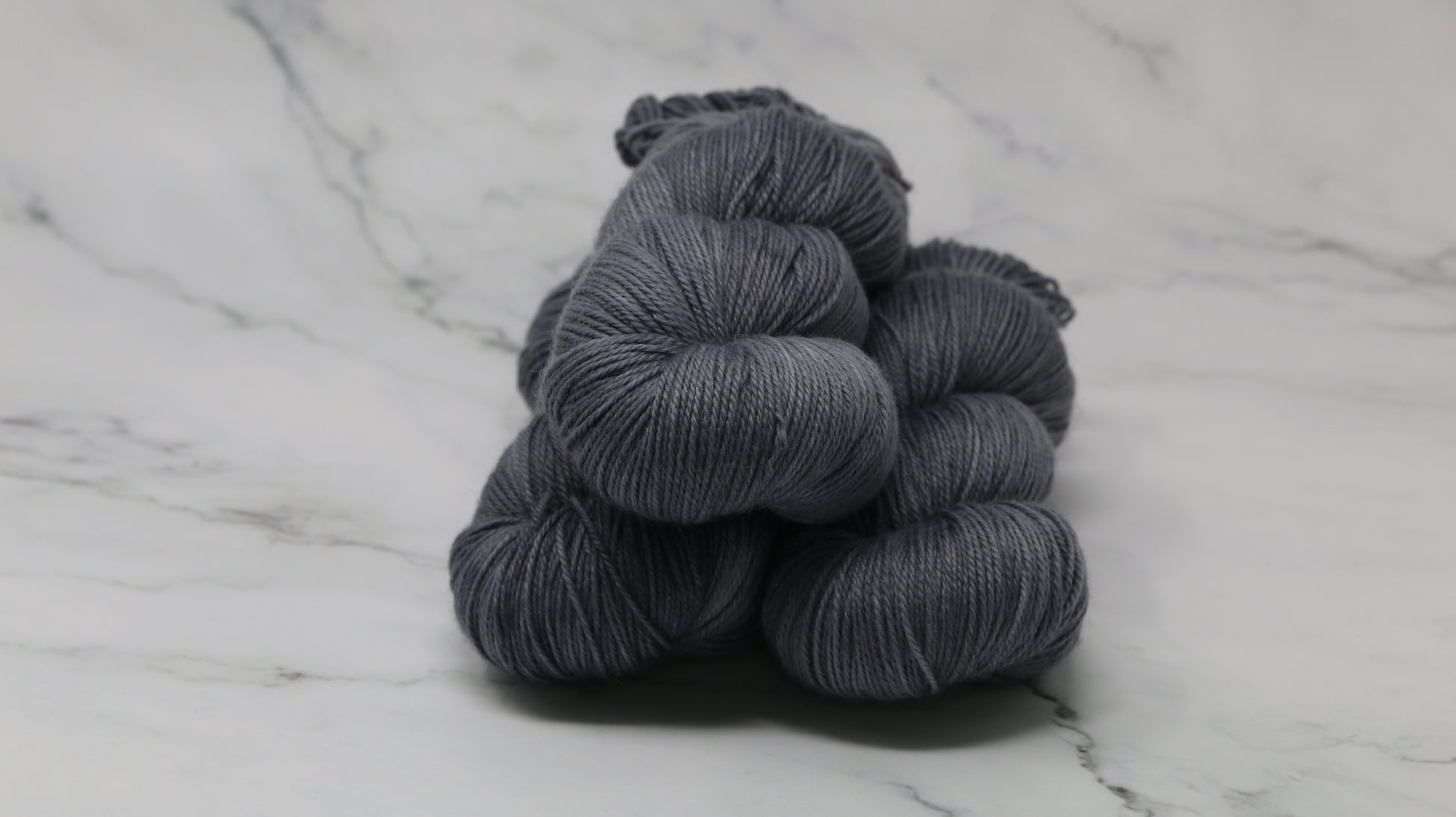 Three skeins of yarn in a tonal dark grey colour