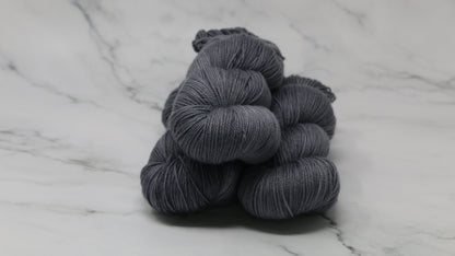 Three skeins of yarn in a tonal dark grey colour