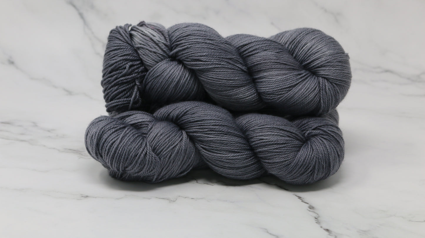Three skeins of yarn in a tonal dark grey colour