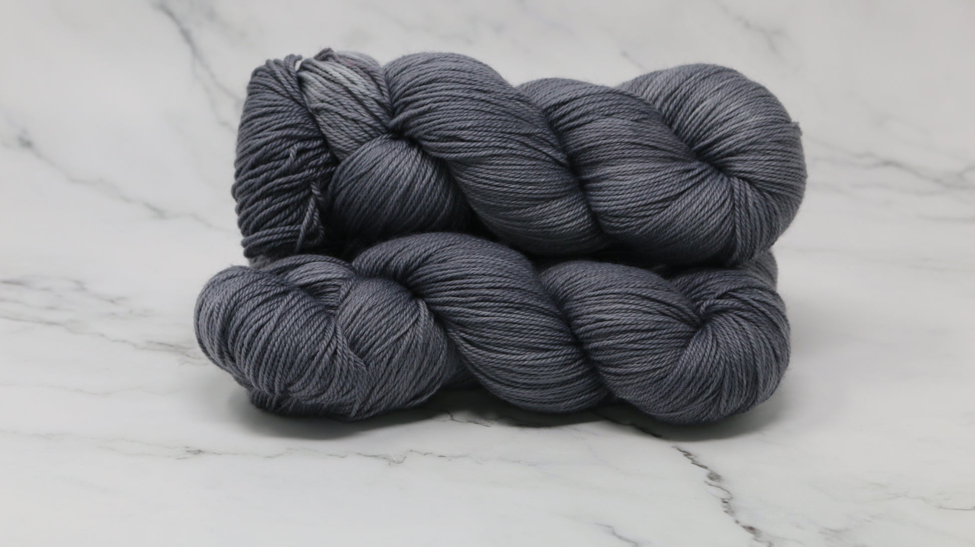 Three skeins of yarn in a tonal dark grey colour