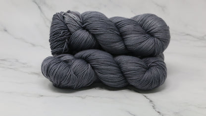 Three skeins of yarn in a tonal dark grey colour