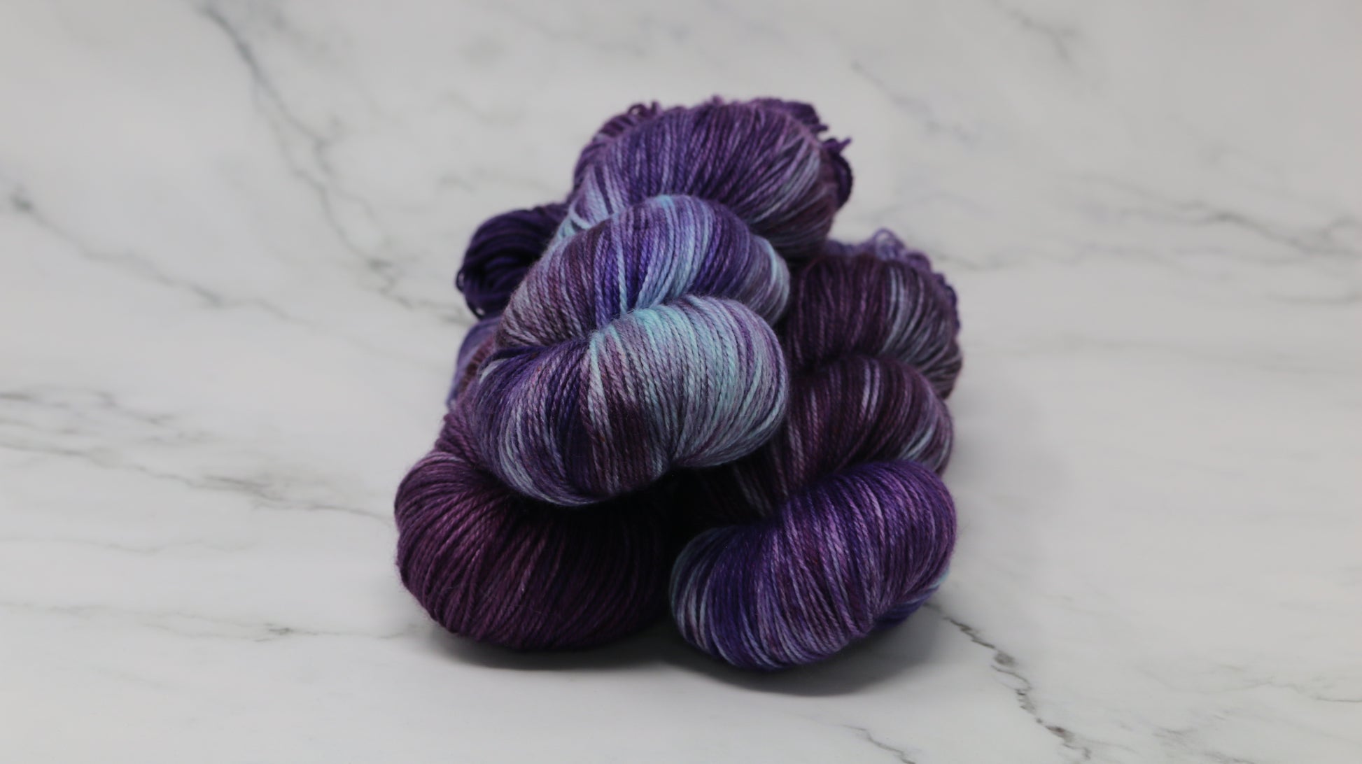 Three skeins of variegated purple and blue yarn