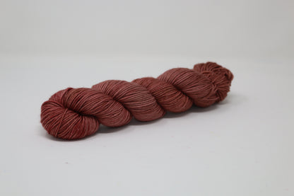 A skein of tonal red/brown yarn on a white surface and background