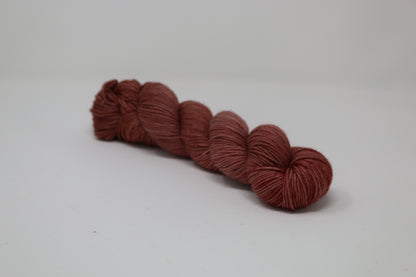 A skein of tonal red/brown yarn on a white surface and background