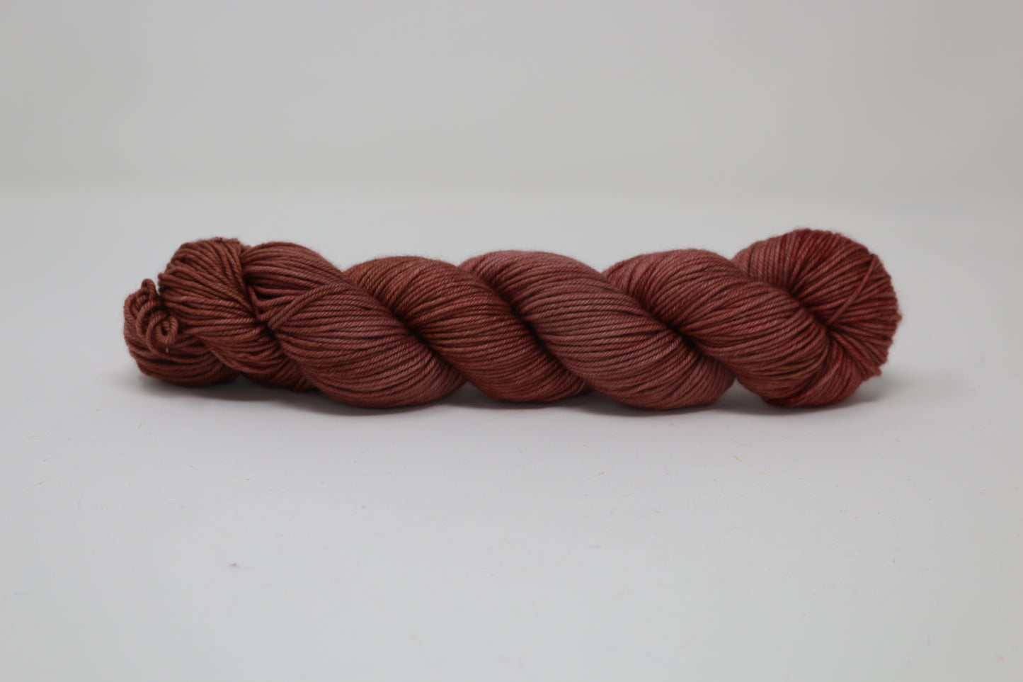 A skein of tonal red/brown yarn on a white surface and background
