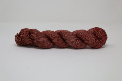 A skein of tonal red/brown yarn on a white surface and background