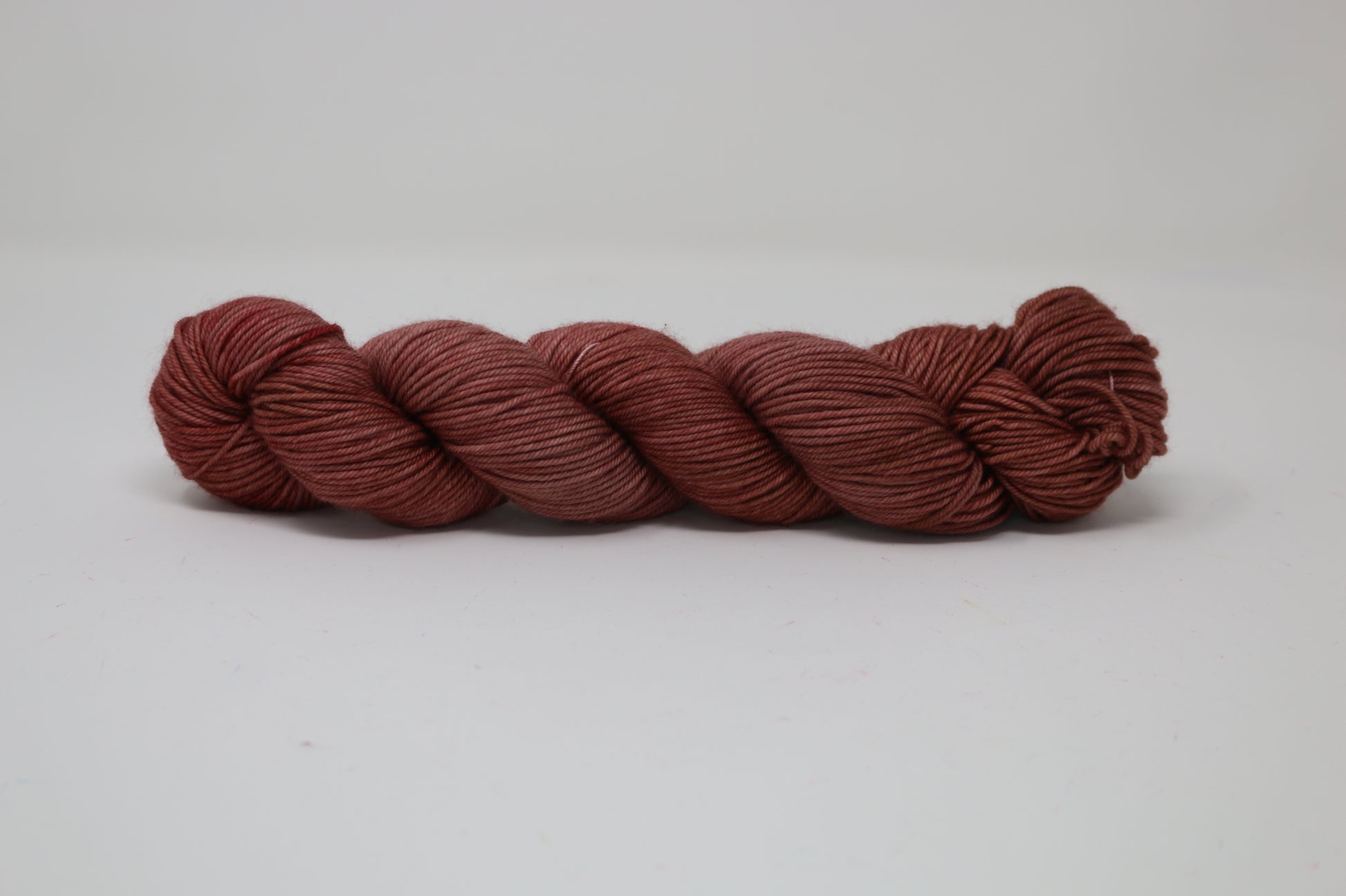 A skein of tonal red/brown yarn on a white surface and background