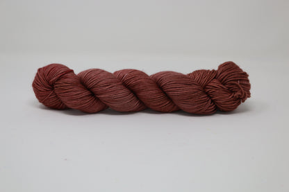 A skein of tonal red/brown yarn on a white surface and background
