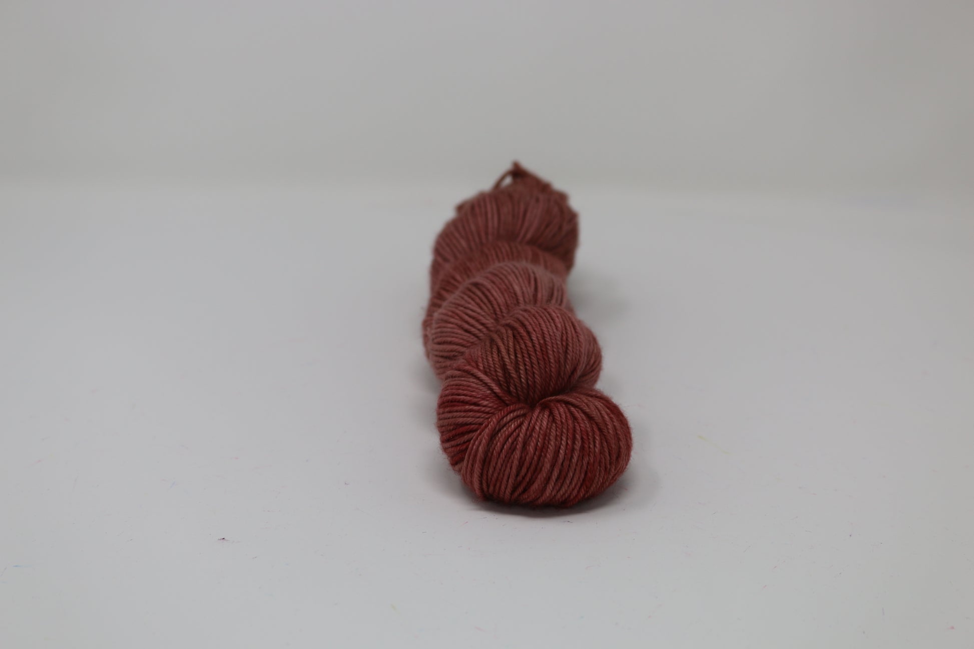 A skein of tonal red/brown yarn on a white surface and background