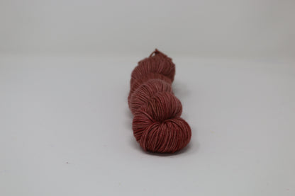 A skein of tonal red/brown yarn on a white surface and background