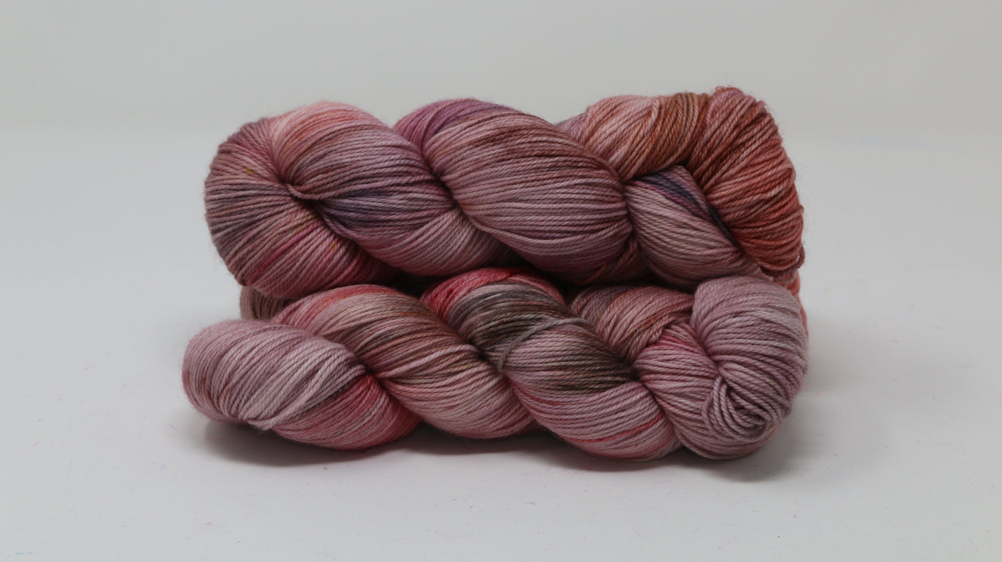 Three skeins of yarn in dusty rose, mauve, and terracotta tones