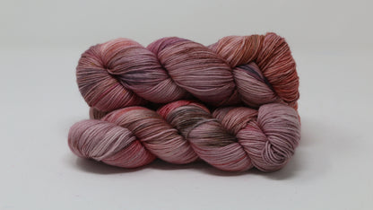 Three skeins of yarn in dusty rose, mauve, and terracotta tones