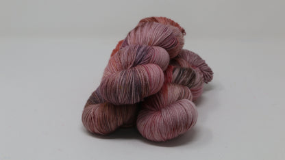 Three skeins of yarn in dusty rose, mauve, and terracotta tones