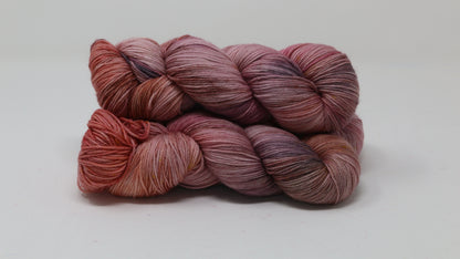 Three skeins of yarn in dusty rose, mauve, and terracotta tones