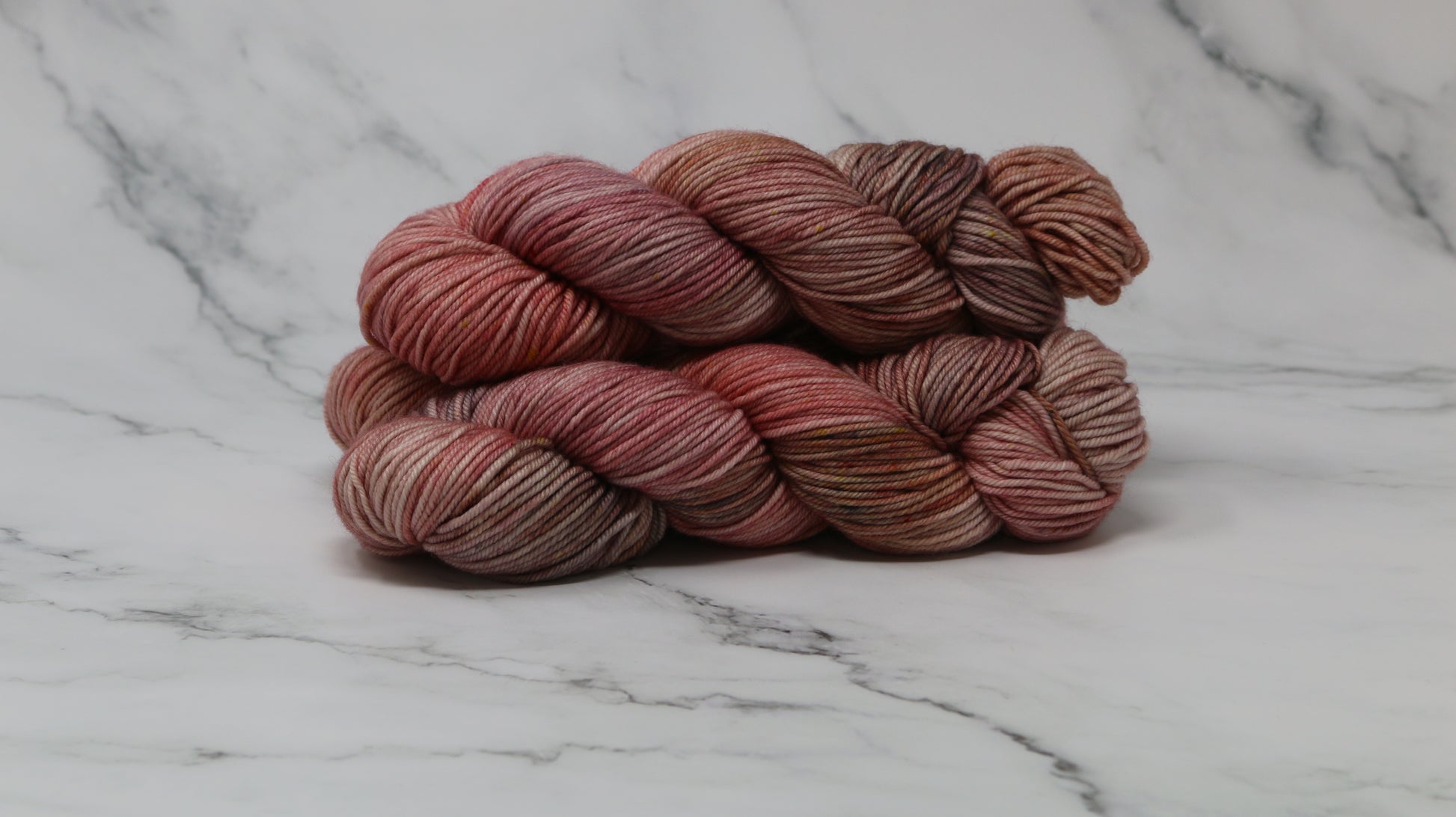 3 skeins of variegated yarn on a white marble surface and background