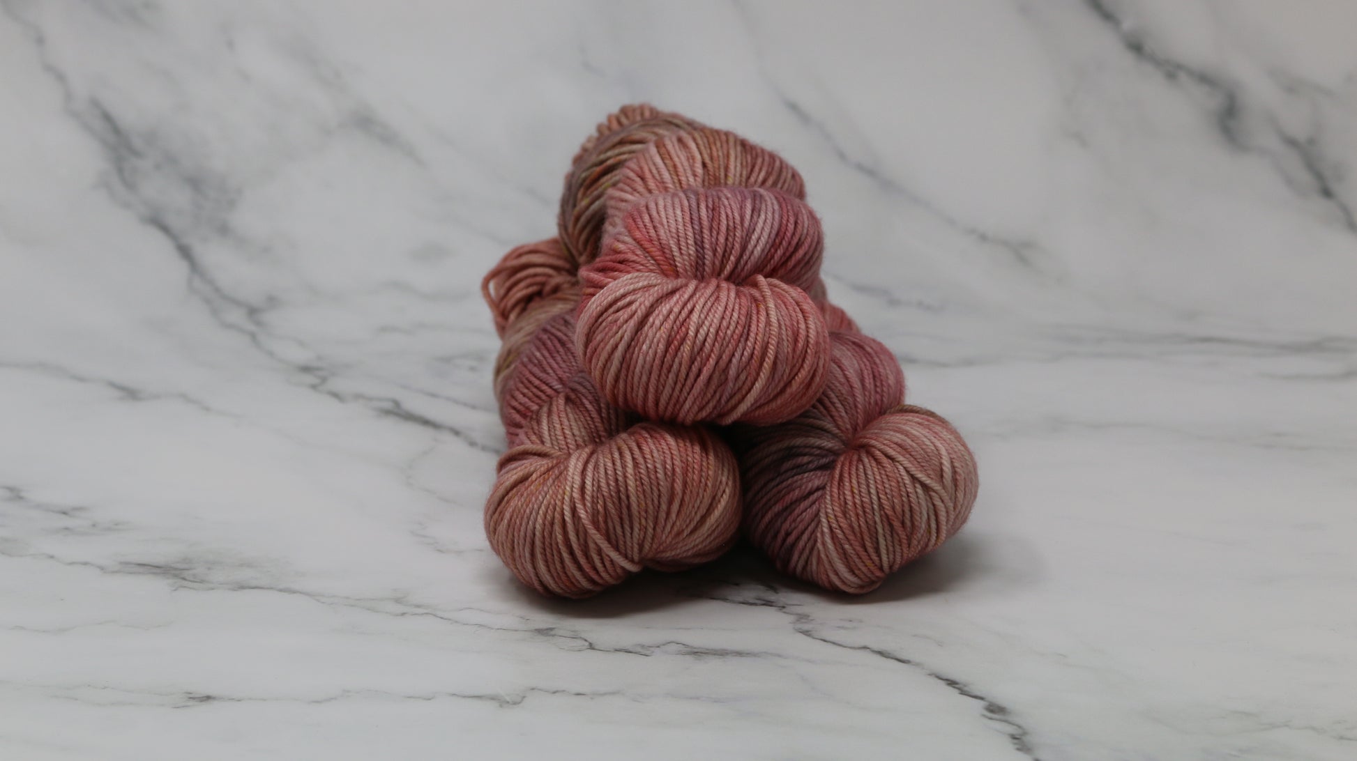 3 skeins of variegated yarn on a white marble surface and background