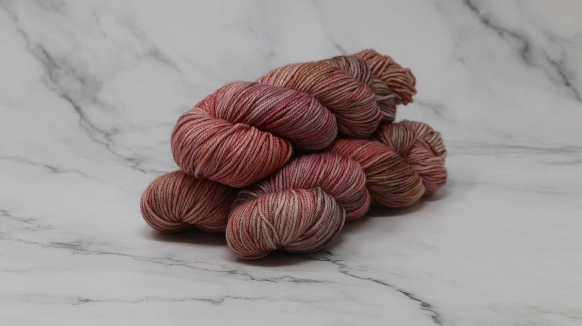 3 skeins of variegated yarn on a white marble surface and background