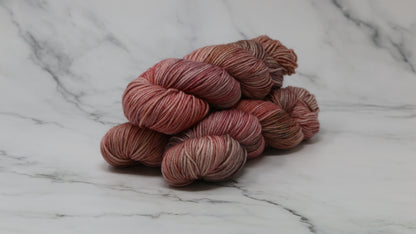 3 skeins of variegated yarn on a white marble surface and background