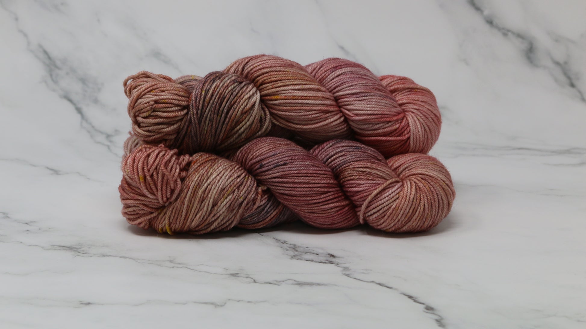 3 skeins of variegated yarn on a white marble surface and background