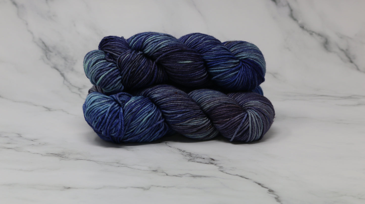 3 skeins of blue variegated yarn on a white marble background and surface