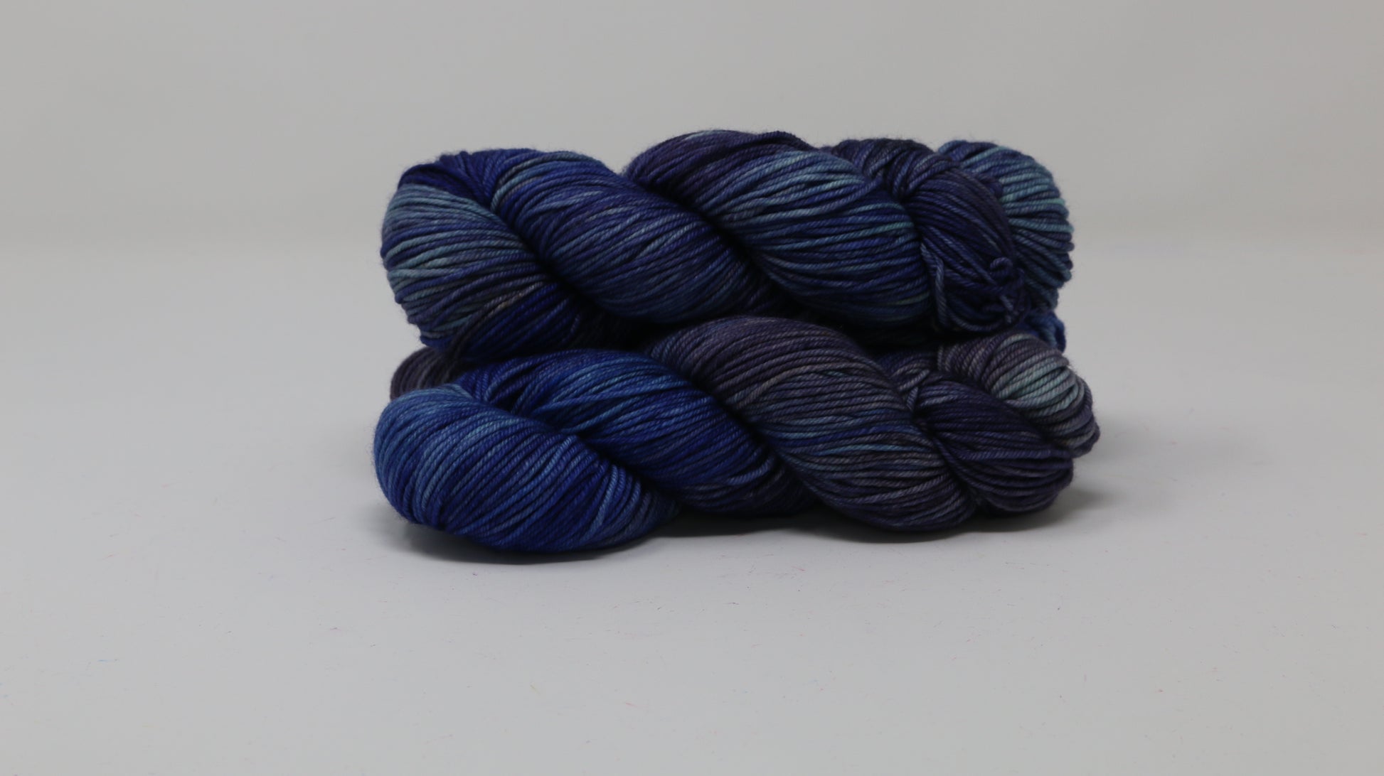 3 skeins of blue variegated yarn on a white background and surface