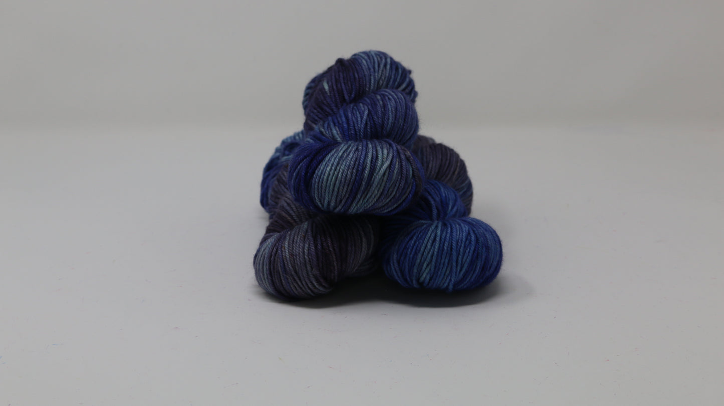 3 skeins of blue variegated yarn on a white background and surface