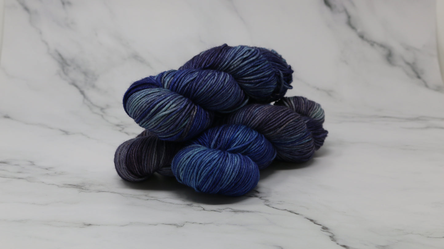 3 skeins of blue variegated yarn on a white marble background and surface