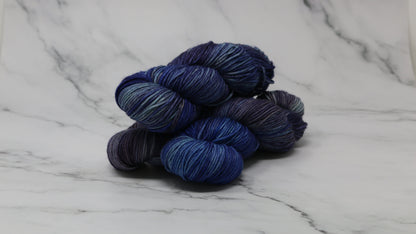 3 skeins of blue variegated yarn on a white marble background and surface