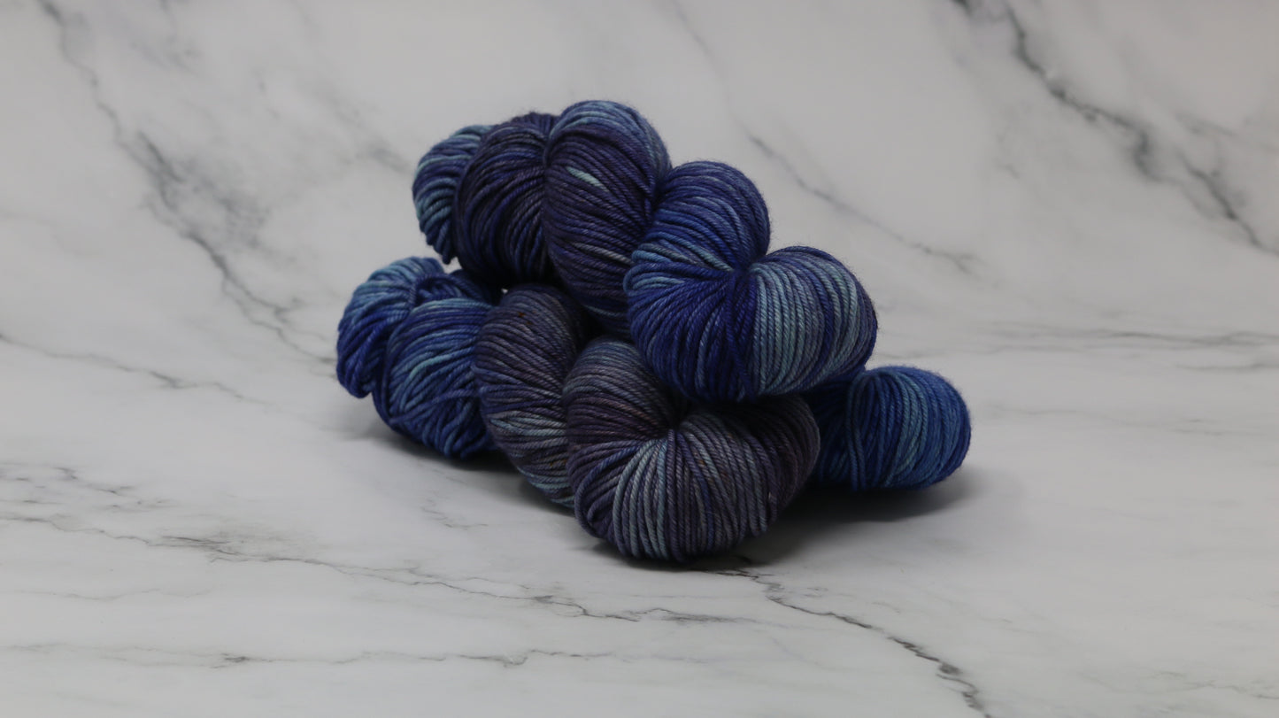3 skeins of blue variegated yarn on a white marble background and surface