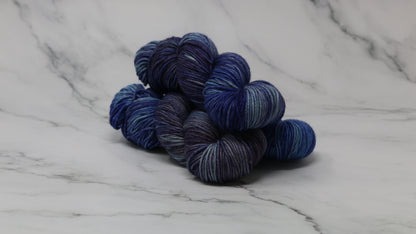 3 skeins of blue variegated yarn on a white marble background and surface