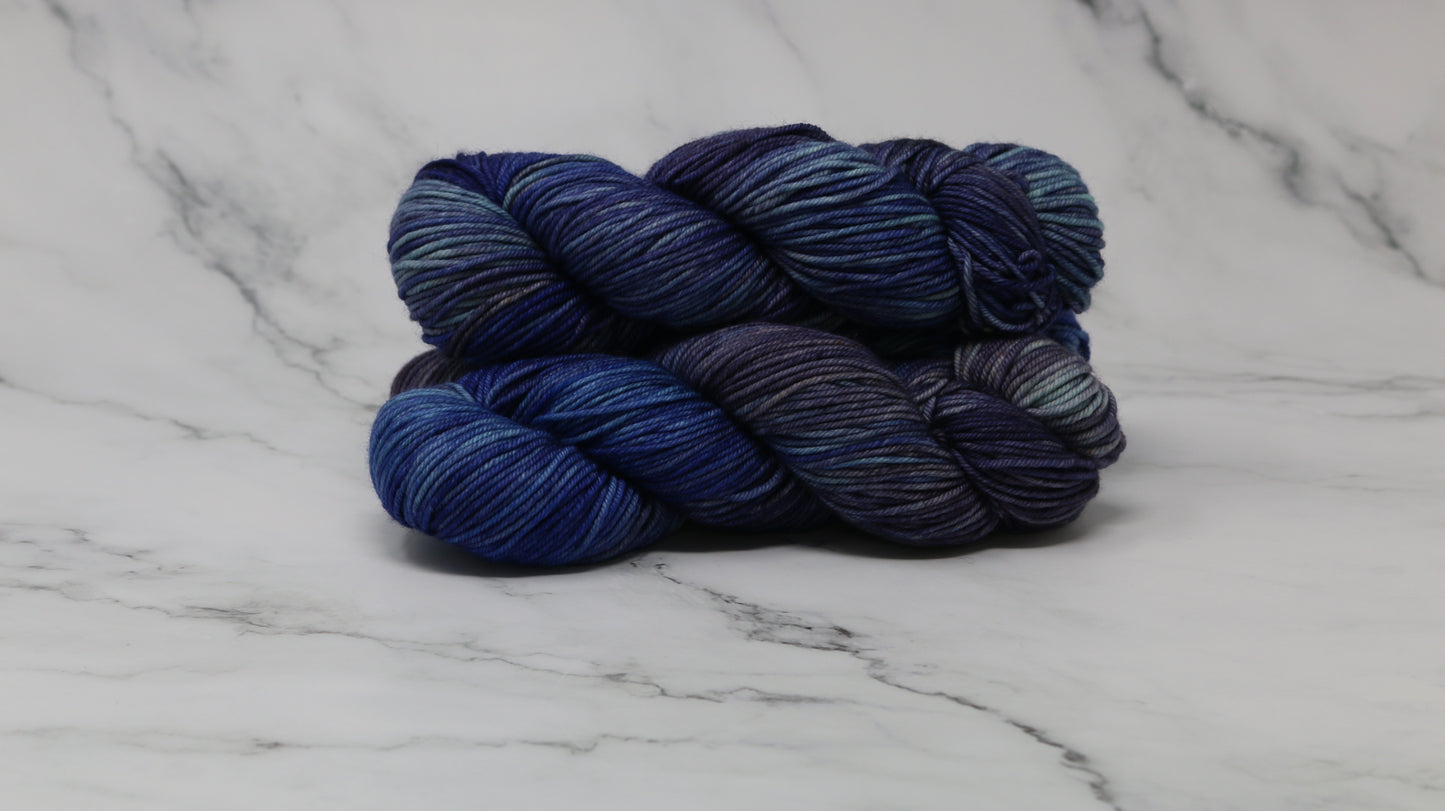 3 skeins of blue variegated yarn on a white marble background and surface
