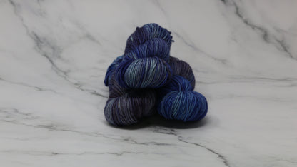 3 skeins of blue variegated yarn on a white marble background and surface