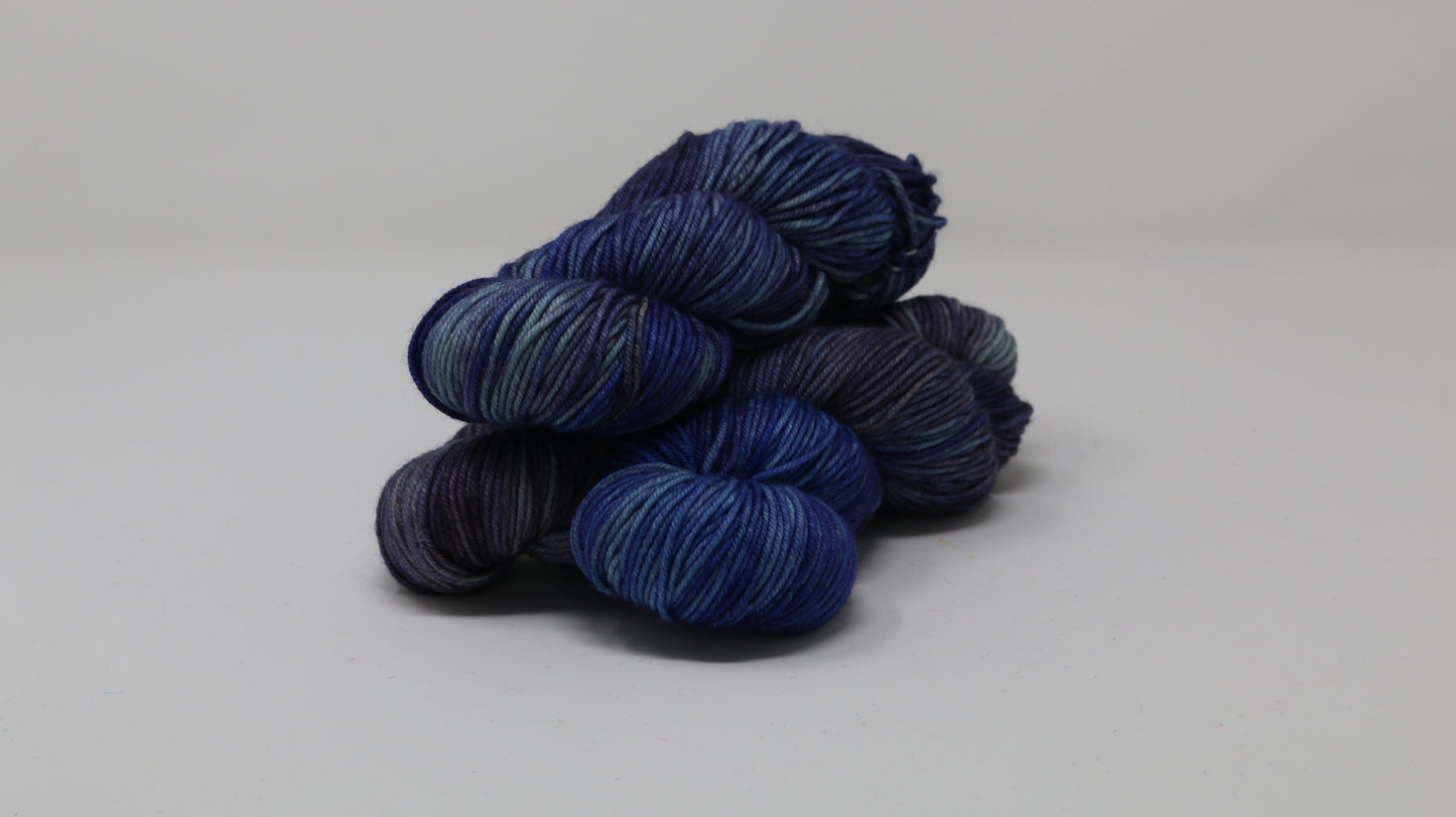 3 skeins of blue variegated yarn on a white background and surface