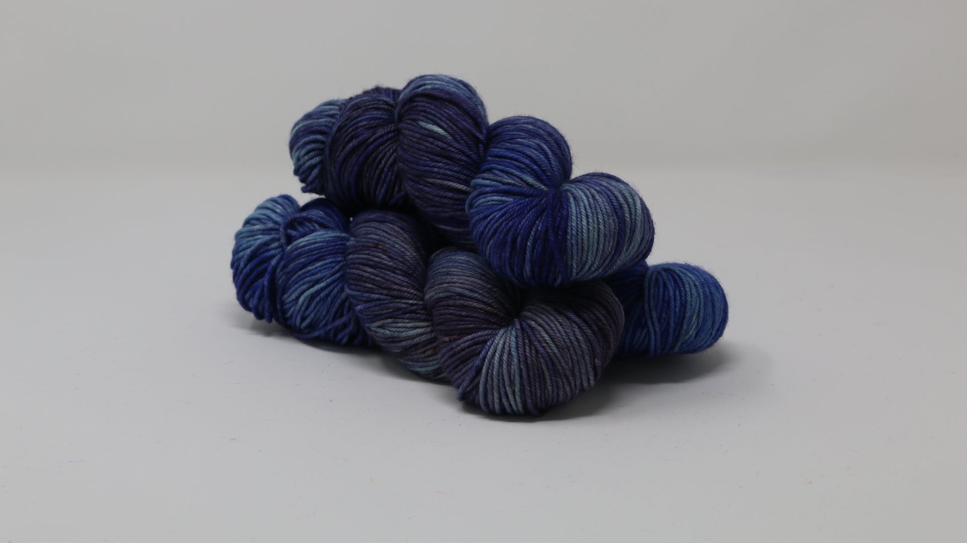 3 skeins of blue variegated yarn on a white background and surface