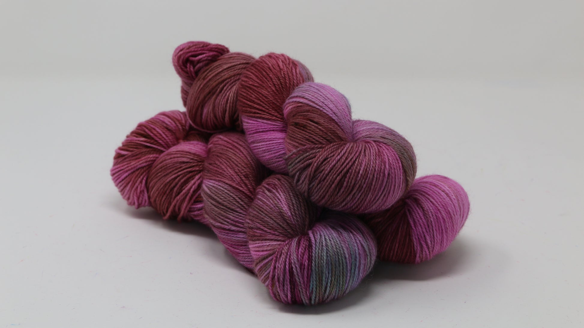 3 skeins of pink, red, green yarn