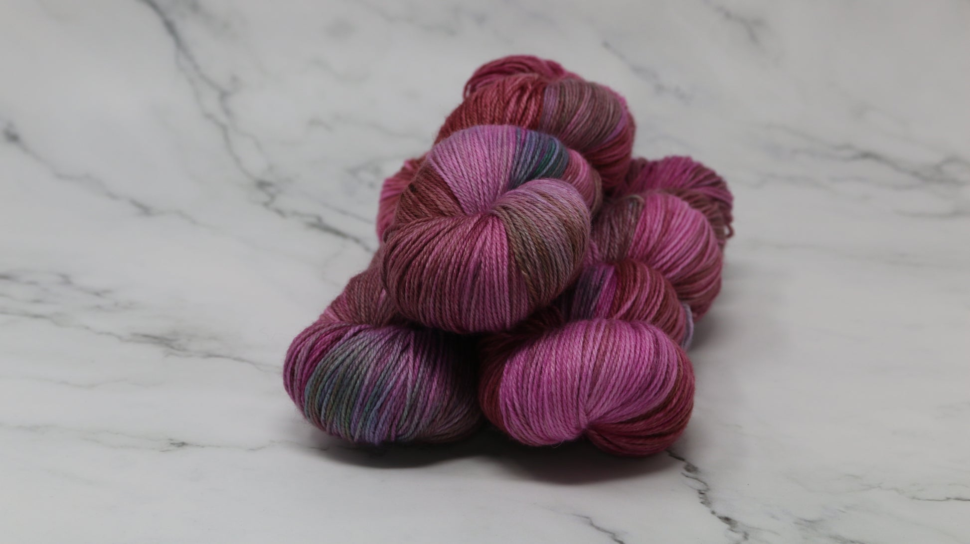 3 skeins of pink, red, green yarn